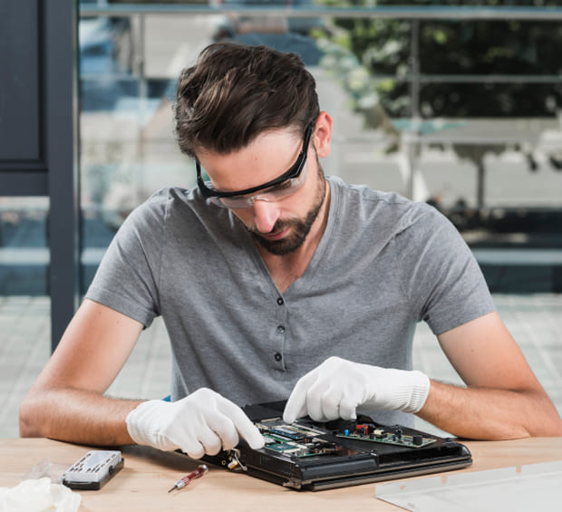 IT Technician Repairing a Laptop on a Workbench